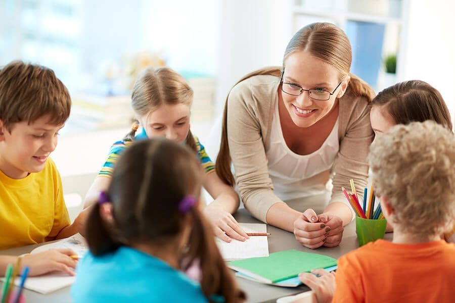 teacher and school-age kids at a table