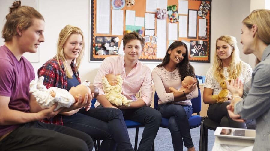 Group of adults sitting in a circle holding baby dolls