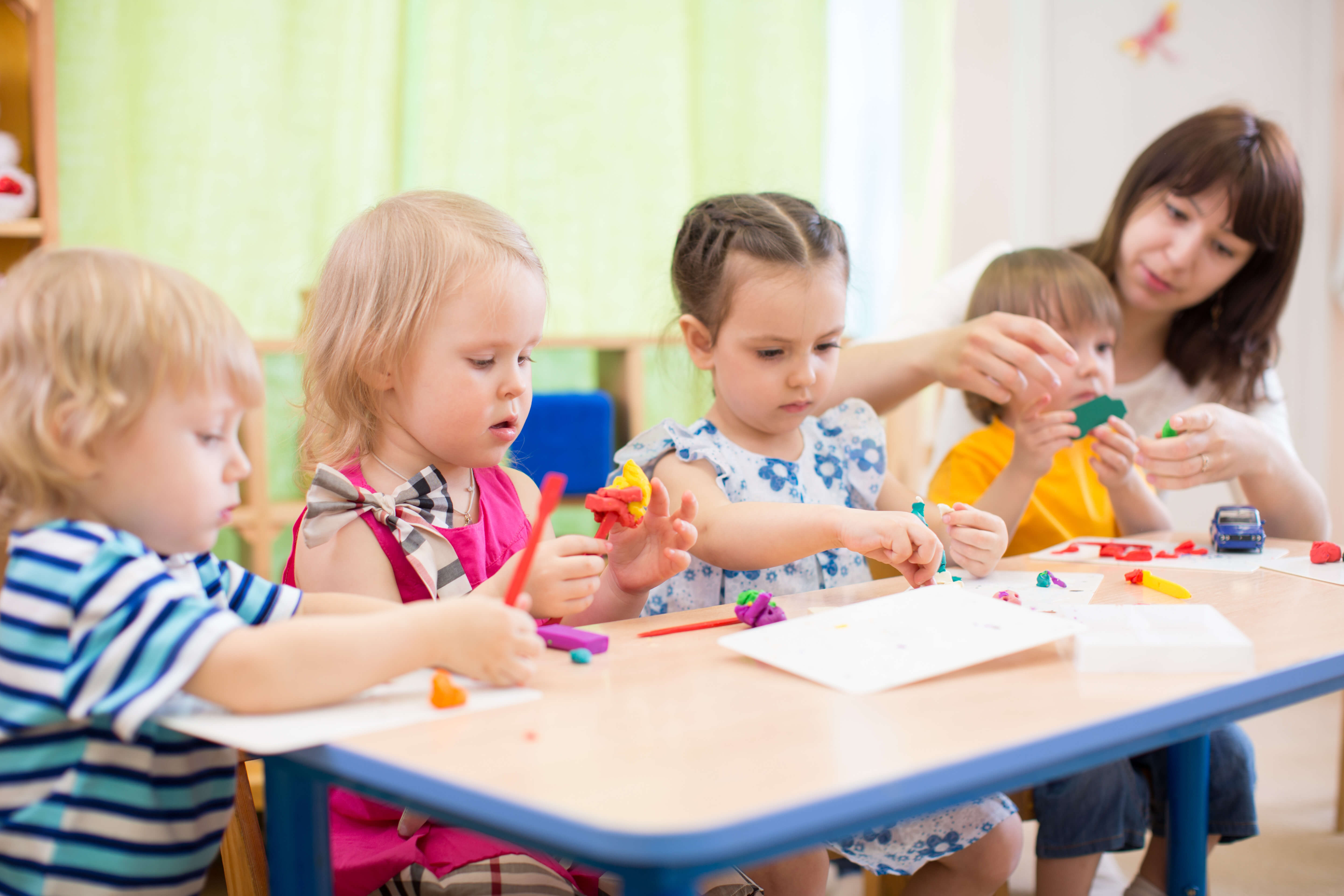 Teacher and three children playing with toys Woman and three children playing with toys