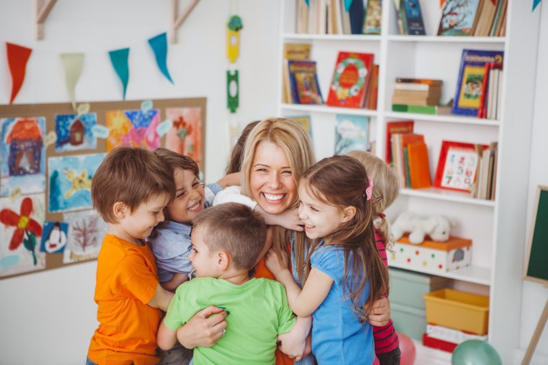 We love our teacher Kids in kindergarten hugging their teacher