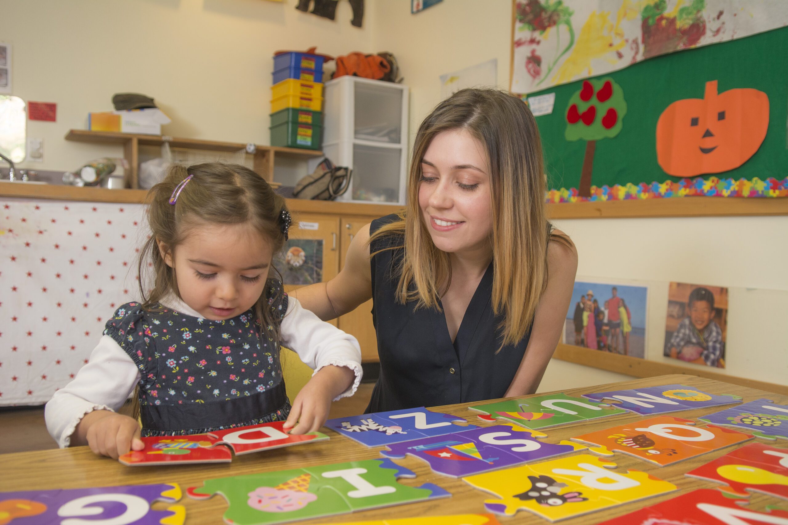 preschool teacher reads a book with a young girl