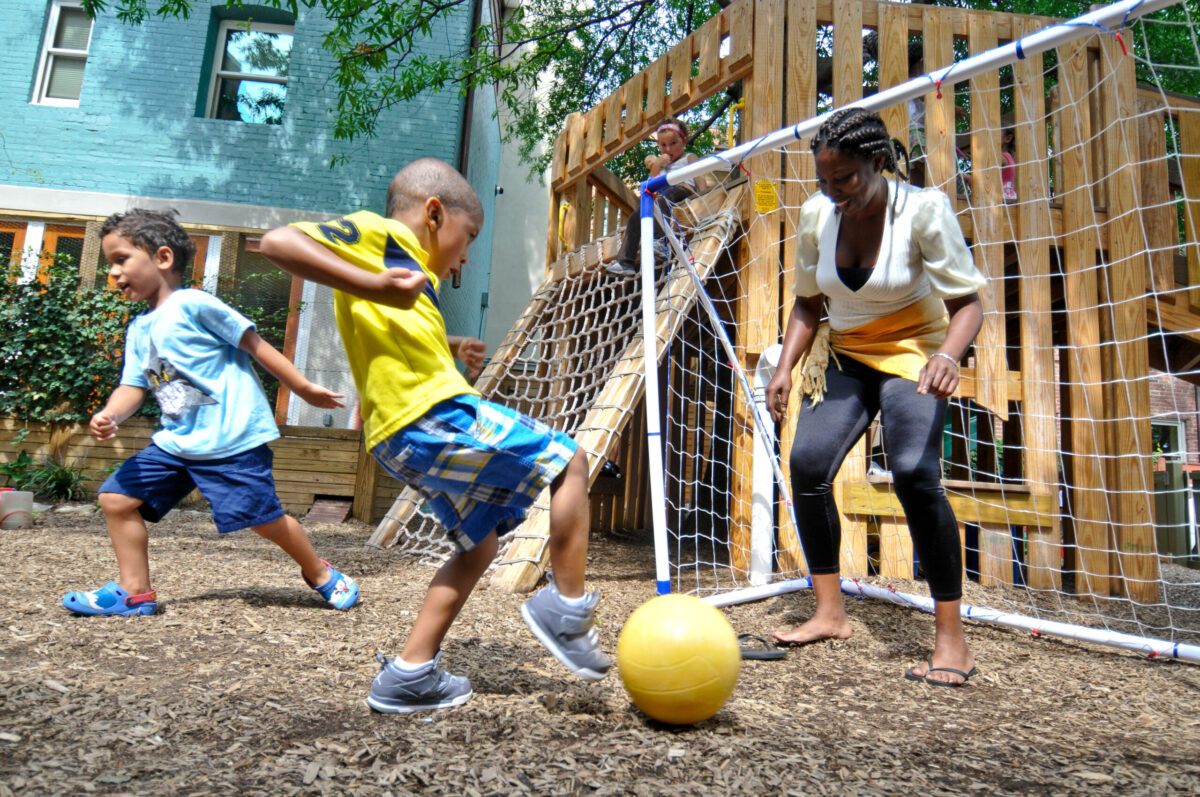 Boy plays soccer with his child care teacher