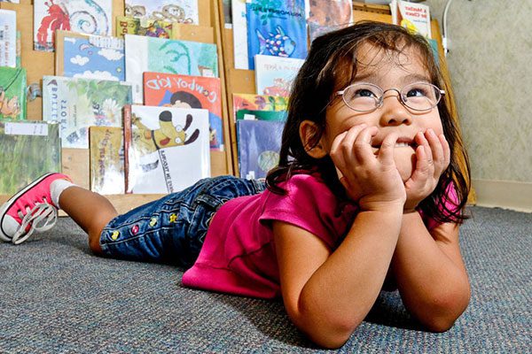 benchmark-featured girl laying down in front of a book case