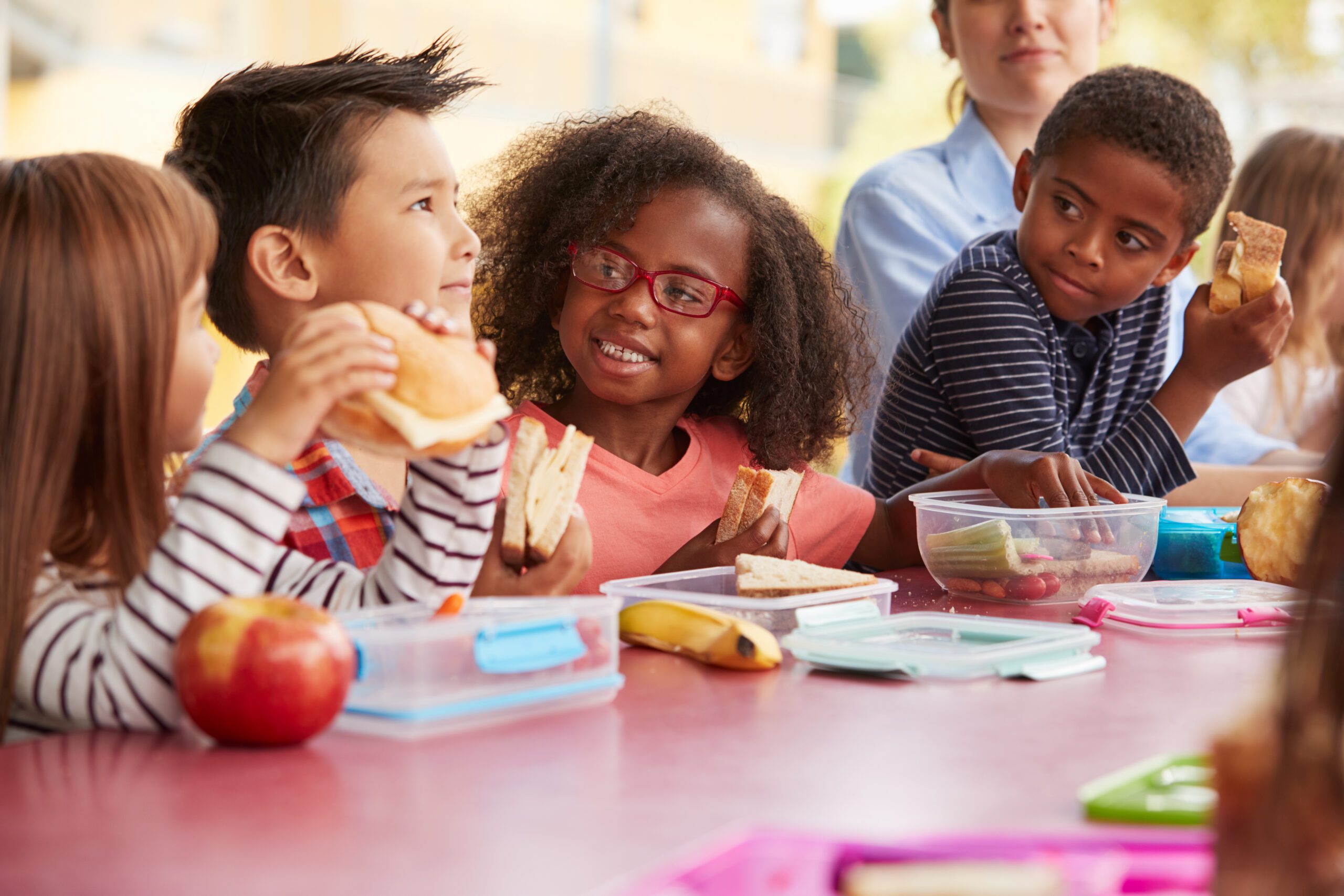 Young,School,Kids,Eating,Lunch,Talking,At,A,Table,Together
